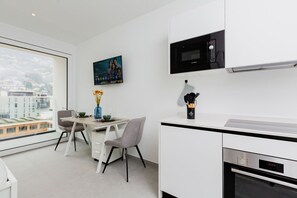 A modern kitchen with a microwave, oven, and dining area with chairs and a table. - {Suite 610} Gym, Business Room, Modern, Relax (Lugano)