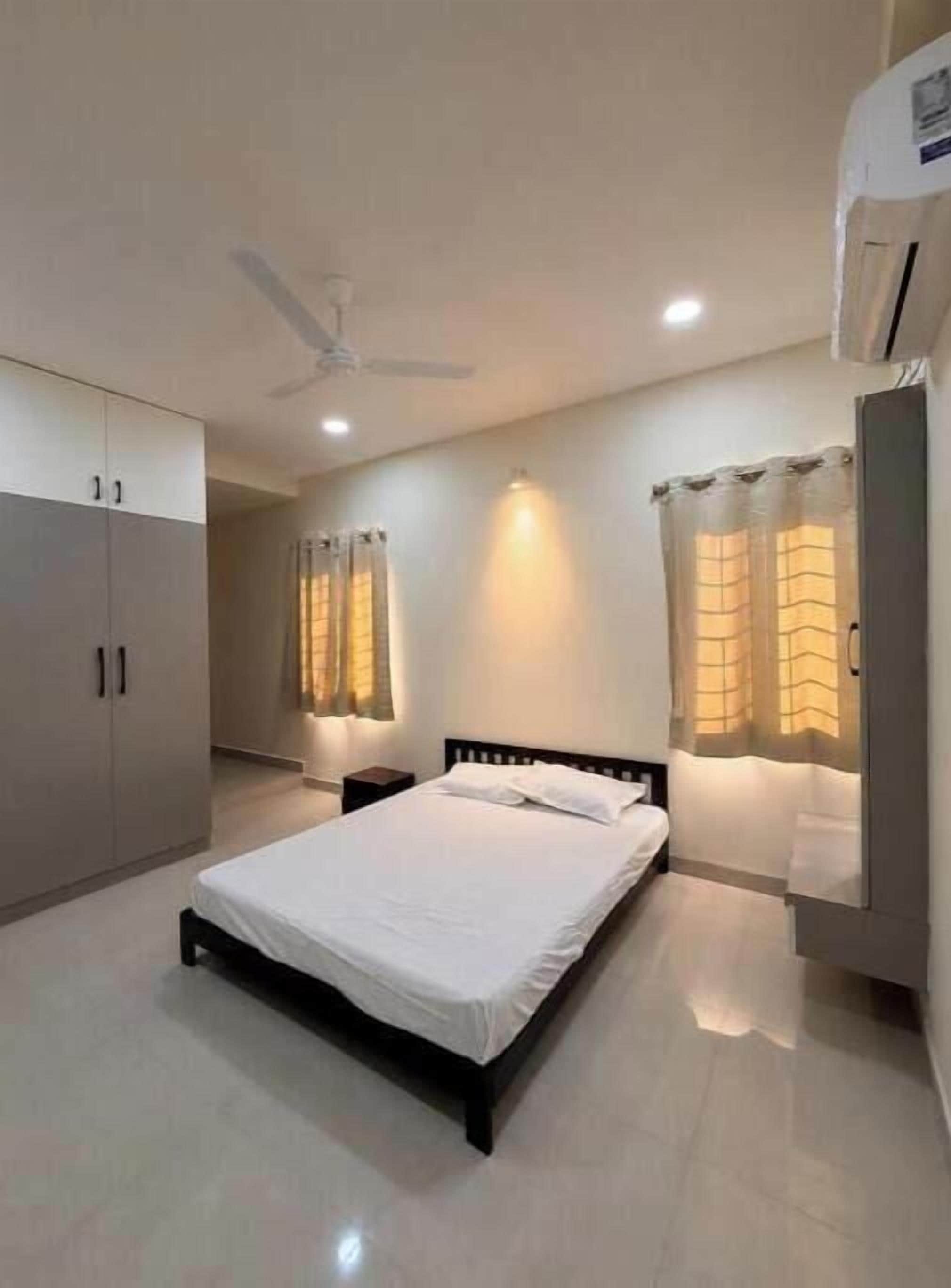 Une chambre à coucher comprenant un lit, une armoire, un ventilateur de plafond et un appareil de climatisation.