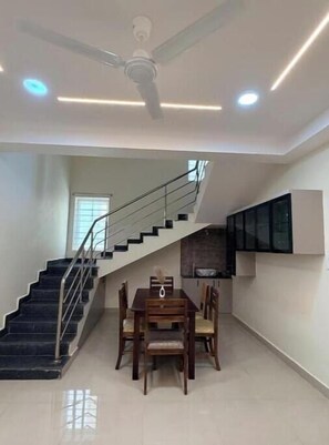 Ein modernes Interieur mit Treppe, Essbereich, Deckenventilator, eingelassener Beleuchtung und einem an der Wand befestigten Flachbildfernseher.