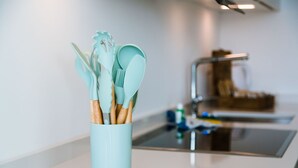 Een keuken met een lichtblauwe messenhouder met keukengerei met houten handgrepen.