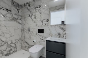 A bathroom with marble walls, a white toilet, a shower, and a sink with a mirror. - {Suite 611} Gym, Business Room, Modern, Relax (Lugano)