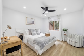 A bedroom with a bed, bedside table, lamp, chair, window, and ceiling fan. - Stunning Lakefront Haven with Private Dock and Hot Tub (Blakeslee)