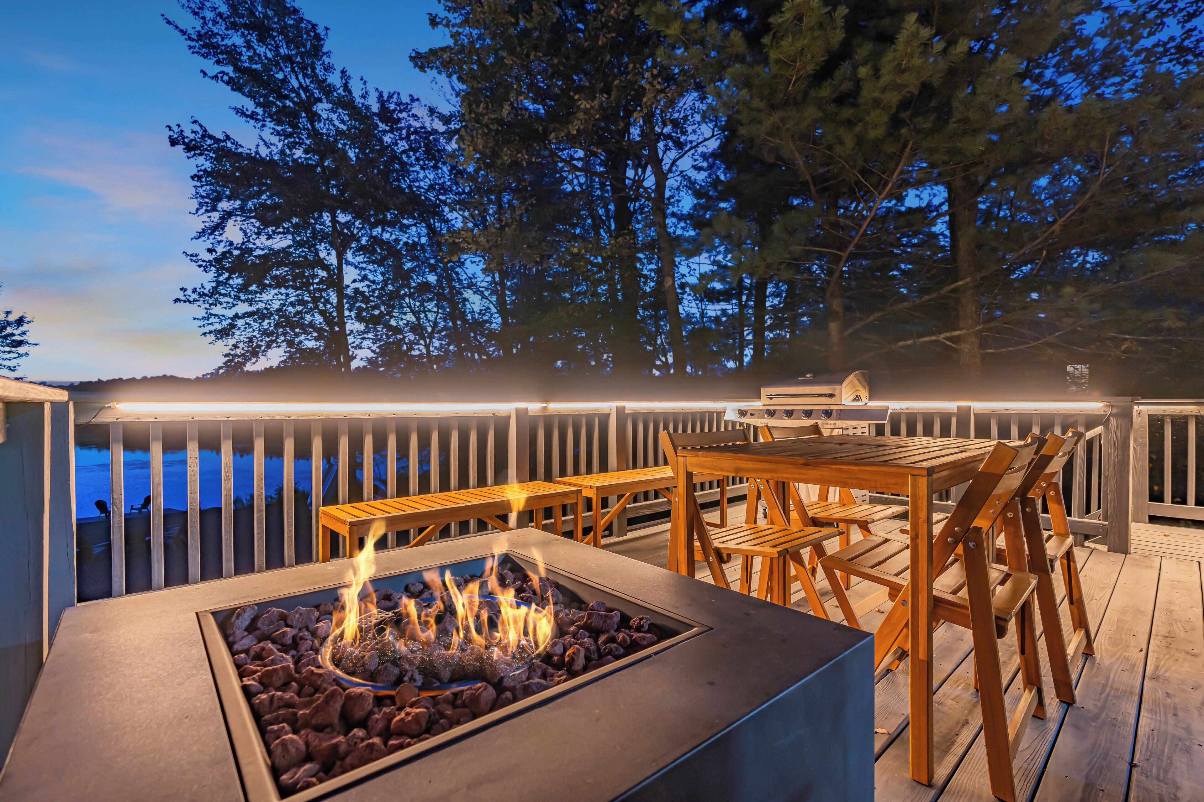 An outdoor deck with a fire pit, wooden furniture, and a view of the forest.