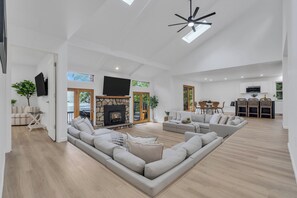 A spacious living area with a fireplace, seating, and a view of the outdoors. - Stunning Lakefront Haven with Private Dock and Hot Tub (Blakeslee)