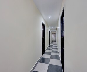A corridor with a checkered floor, doors on both sides, and a ceiling light. - Deluxe Hotel O Satyam Junction (Visakhapatnam)