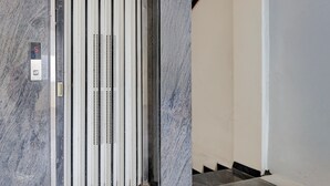 Hissi, jossa on digitaalinen näyttö, metalliset ovet ja ruutukuviollinen lattia.