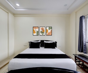 A hotel room with a bed, a desk, and three framed artworks on the wall. - Deluxe Hotel O Satyam Junction (Visakhapatnam)