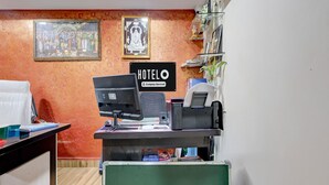 Hotellin vastaanottotiski, jossa on tietokone, puhelin ja kyltti, josta ilmenee, että hotelli on yrityksen hallinnoima.