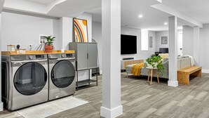 A modern laundry room with a washing machine and dryer, a wooden counter, and a potted plant. - Modern 3-Bed, 2-Bath with AC in Everett Near Downtown, Airport, City & Encore (Everett)