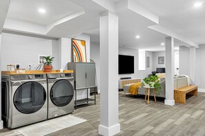 A modern laundry room with a washing machine and dryer, a wooden counter, and a potted plant. - Modern 3-Bed, 2-Bath with AC in Everett Near Downtown, Airport, City & Encore (Everett)
