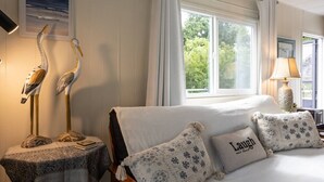 A room with a bed, two decorative bird sculptures, a window with curtains, and a lamp.