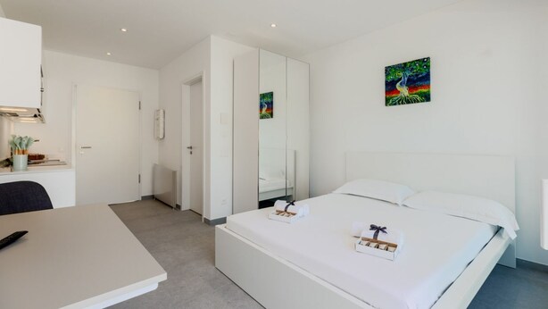 Quarto de hotel moderno com cama, escrivaninha e espelho.