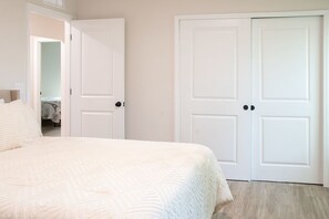 Une chambre à coucher avec un lit, deux portes blanches et un couloir menant à une autre pièce.