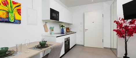 A modern kitchen with white cabinetry, a microwave, and a dining area with a table and chairs.