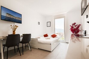 A modern bedroom with a bed, a desk with chairs, a TV, and a balcony with a view. - {Suite 613} Gym, Business Room, Modern, Relax (Lugano)