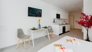 Ett modernt hotellrum med en matplats, ett kök och en stor TV-skärm.