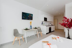 A modern hotel room with a dining area, a kitchen, and a large TV screen. - {Suite 614} Gym, Business Room, Modern, Relax (Lugano)
