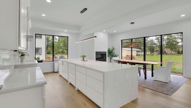 A modern kitchen with a large island, white cabinetry, and a dining area with a table and chairs. - Luxury 4-bedroom home with 2 kitchens, hot tub, and gym: Group & Family Retreats (Marietta)