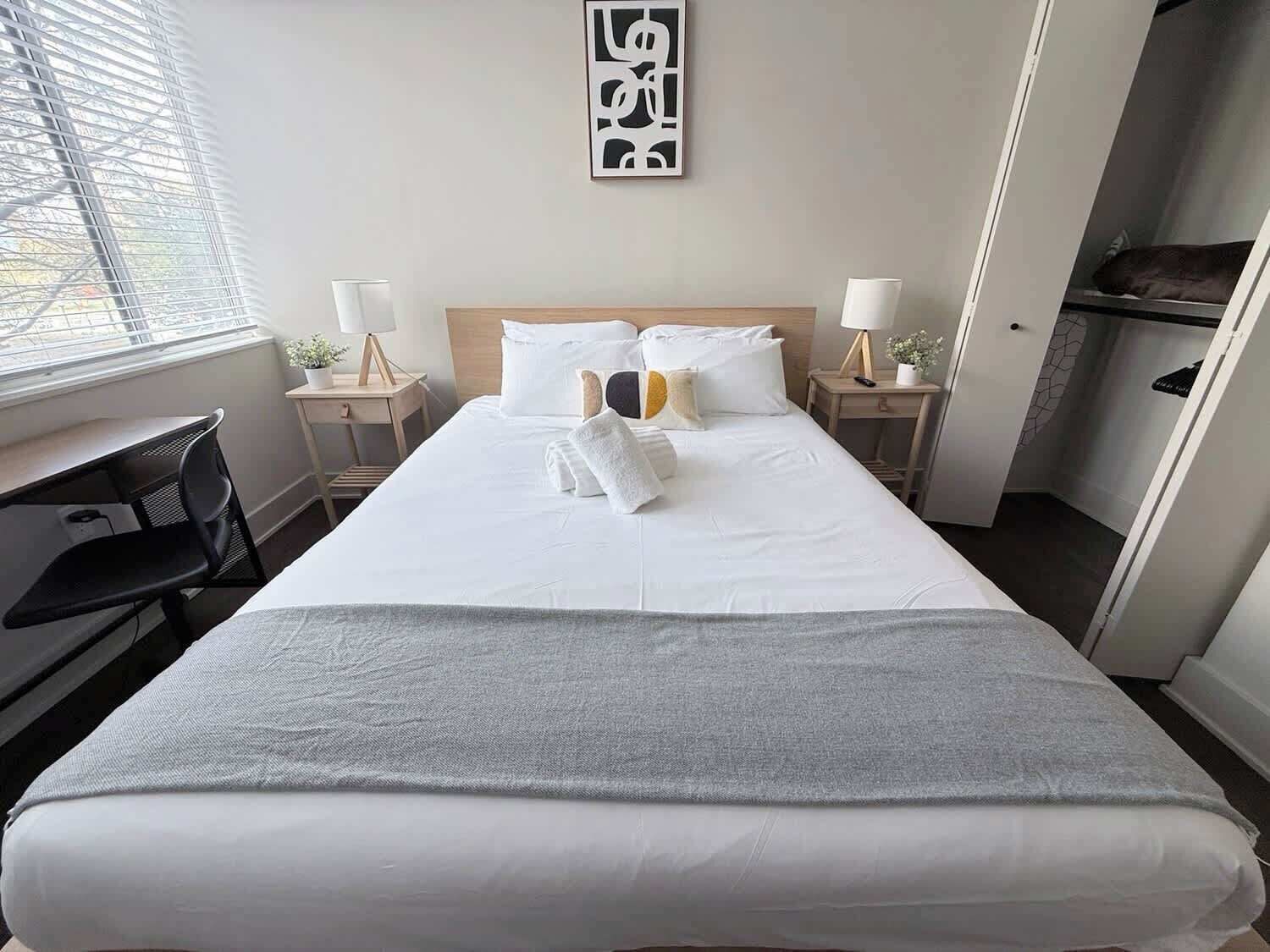 Hotellihuone, jossa on sänky, yöpöydät, työpöytä ja ikkuna.