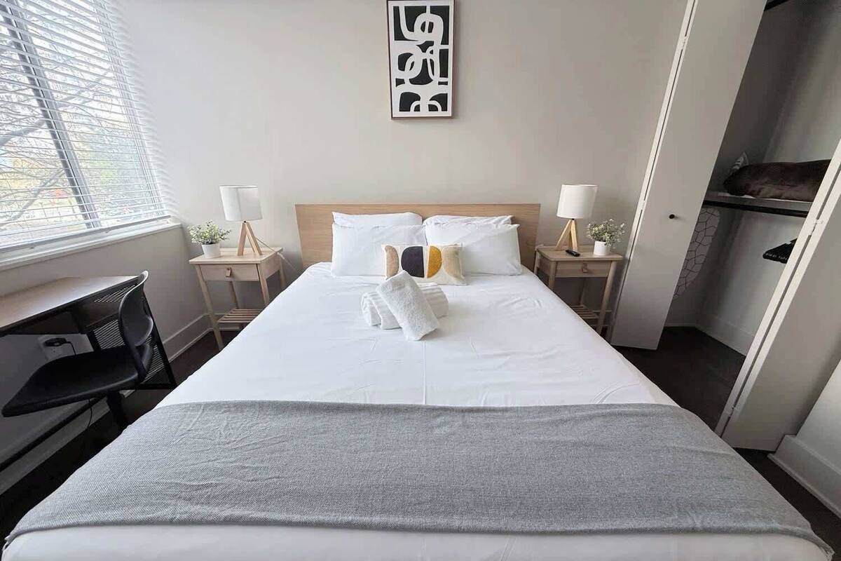 Hotellihuone, jossa on sänky, yöpöydät, työpöytä ja ikkuna.