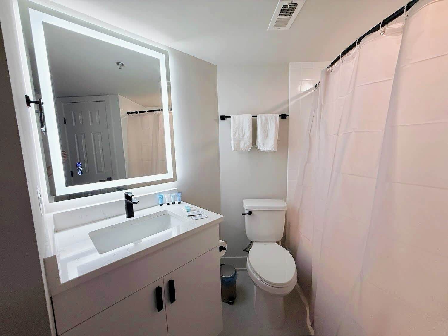 A modern bathroom with a white sink, mirror, and toilet.