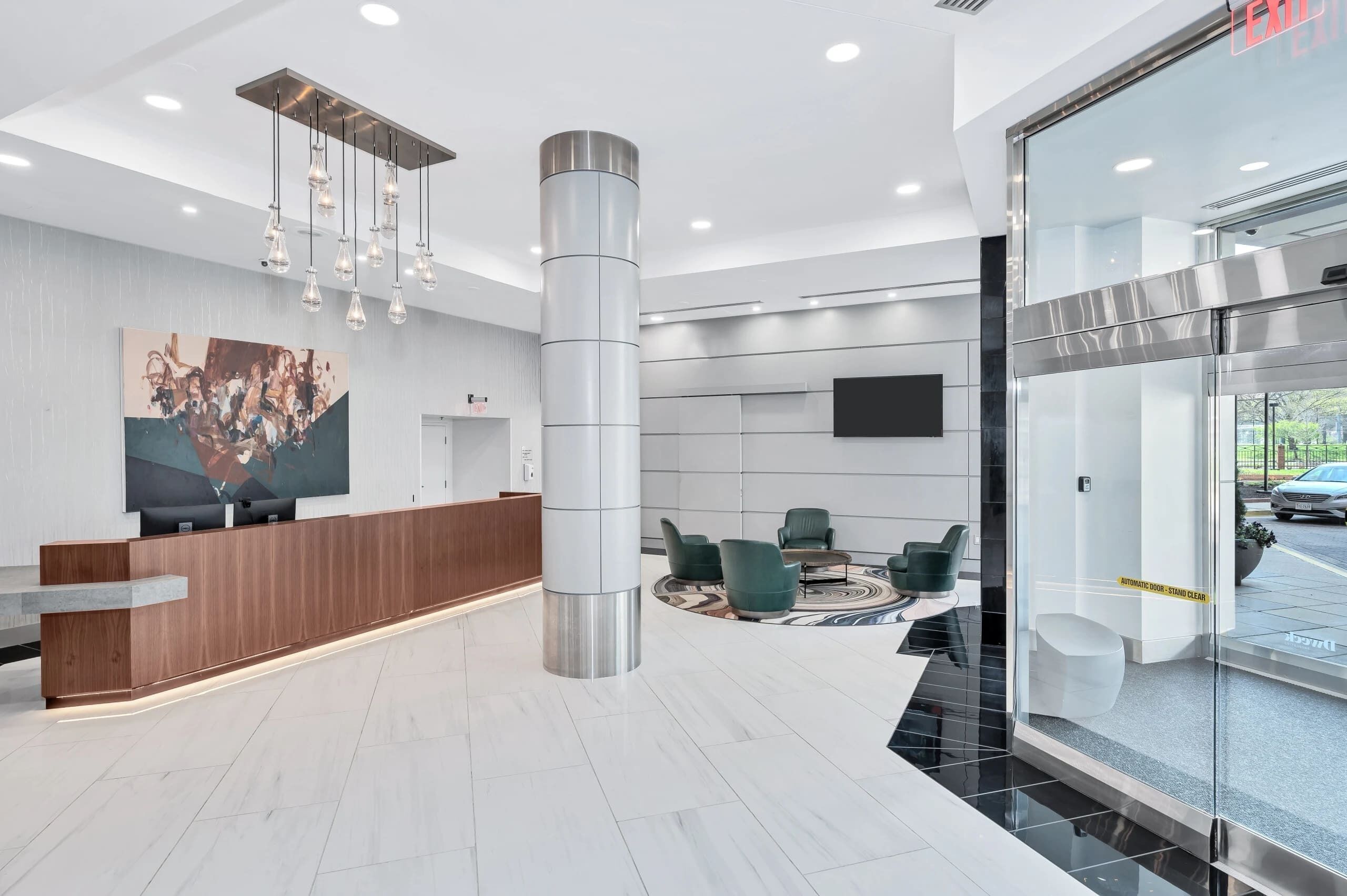 Eine moderne Lobby mit Empfangstresen, Sitzgelegenheiten und einem Glastür-Eingang.
