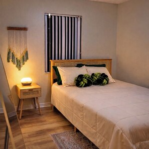 A bedroom with a bed, bedside table, lamp, and a window with blinds. - 5BR Pool Home w/ Fire Pit . Sleeps 10 (Deltona)