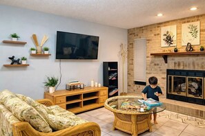 A living room with a television, a fireplace, and a child playing with toys. - 5BR Pool Home w/ Fire Pit . Sleeps 10 (Deltona)