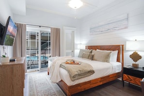 Ein Schlafzimmer mit Bett, Nachttischen, einem Fernseher und Blick auf einen Balkon.