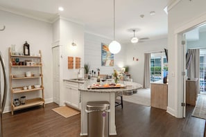 Una cocina moderna con una isla central, estantes de madera y un comedor con vistas.