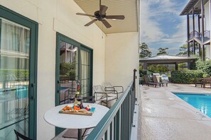 Zona junto a la piscina con mesa lista para comer, asientos exteriores y un ventilador de techo.