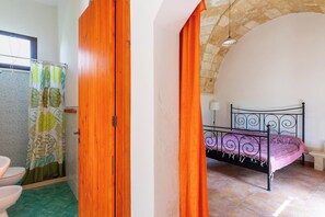 Ein Schlafzimmer mit einem Bett, einer Holztür und einem Badezimmer mit Duschvorhang.