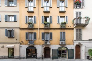 Un immeuble à plusieurs étages doté de balcons, avec un commerce au rez-de-chaussée et un autre commerce dont la façade est en verre.
