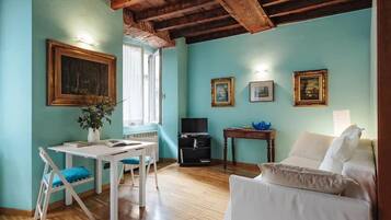 Un salon avec un plafond en bois, un canapé blanc, une table avec des chaises et un meuble pour la télévision.