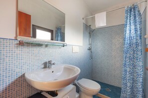 A bathroom with a white sink, a toilet, and a shower with a blue and white checkered shower curtain. - Le Dimore di Casina Litta - La Dependance (Cutrofiano)