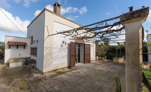 A white building with a tiled roof, a wooden door, and a stone pillar. - Le Dimore di Casina Litta - La Dependance (Cutrofiano)