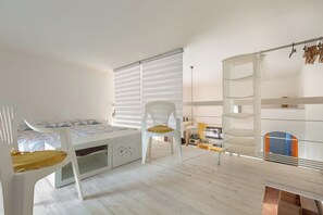 Ein Kinderzimmer mit Etagenbett, Schreibtisch, Stuhl und Regalen.