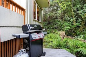 A portable grill on a wooden deck with a house in the background. - Creekside Cabin • Hot Tub, Pool & Ping Pong (Deming)