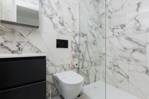 Ein Badezimmer mit Toilette, Dusche und Marmorwand.