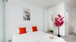 Een moderne hotelkamer met een groot bed, een spiegel, een potplant en kunst aan de muur.