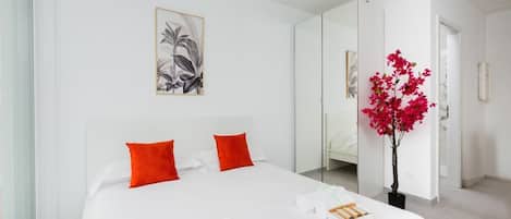 Una habitación de hotel moderna con una cama grande, un espejo, una planta en maceta y obras de arte en la pared.