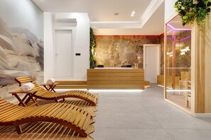Un área de recepción moderna con un mostrador de madera, una zona de estar con sillones de madera y un mural grande en la pared.