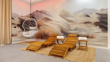 A room with a hanging chair, lounge chairs, and a mural of a mountainous landscape.