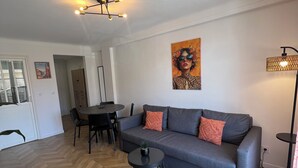 Ein modernes Wohnzimmer mit einer Couch, einem kleinen Tisch, einem Essbereich und einem Bild an der Wand.