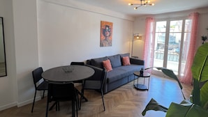 Ein modernes Wohnzimmer mit Esstisch, Sofa und großen Fenstern.