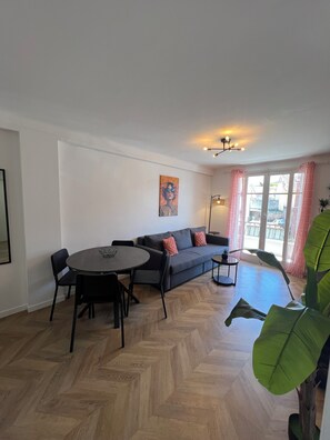 Ein modernes Wohnzimmer mit Esstisch, Sofa und großen Fenstern.