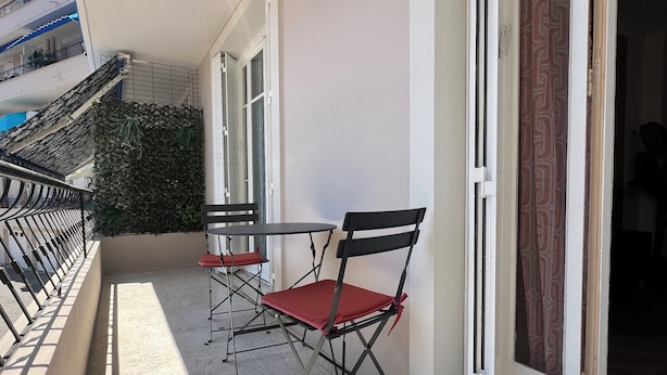 Ein Balkon mit Tisch und Stühlen, einem Blumentopf und einer verzierten Tür.