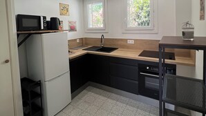 Eine kompakte Küche mit Kühlschrank, Mikrowelle, Spüle und einer kleinen Essecke mit Tisch und Stühlen.