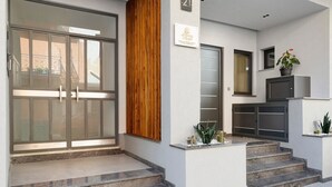 A modern building entrance with a glass door, a wooden panel, and a small potted plant. - Apartment 'La Rocca D'amuri - Alma' with Balcony, Wi-Fi and Air Conditioning (Partinico)