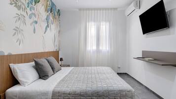 A modern hotel room with a bed, a mounted TV, and a wall-mounted shelf.